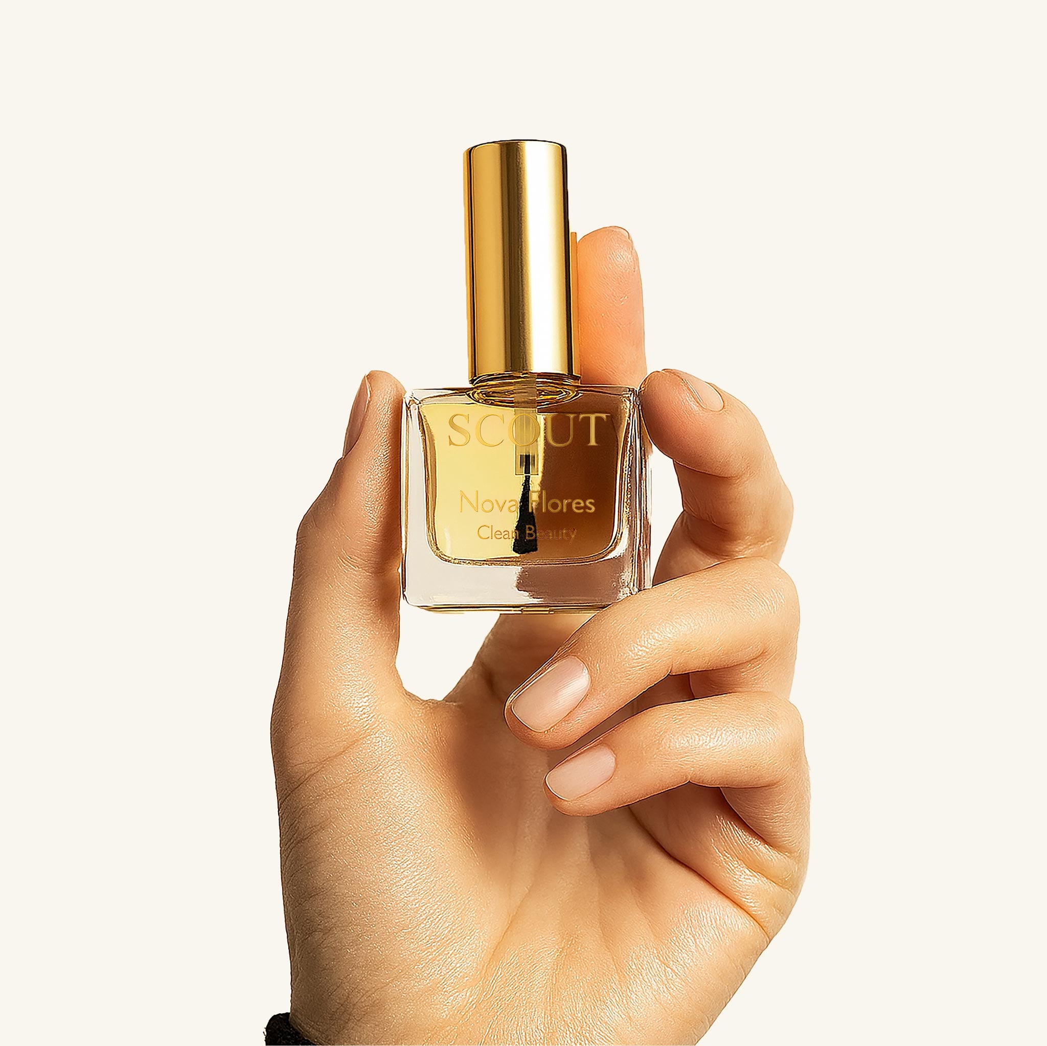 Hand holding SCOUT cuticle oil bottle with gold cap and visible brush, showcasing natural nail care by Australian clean beauty brand on neutral background