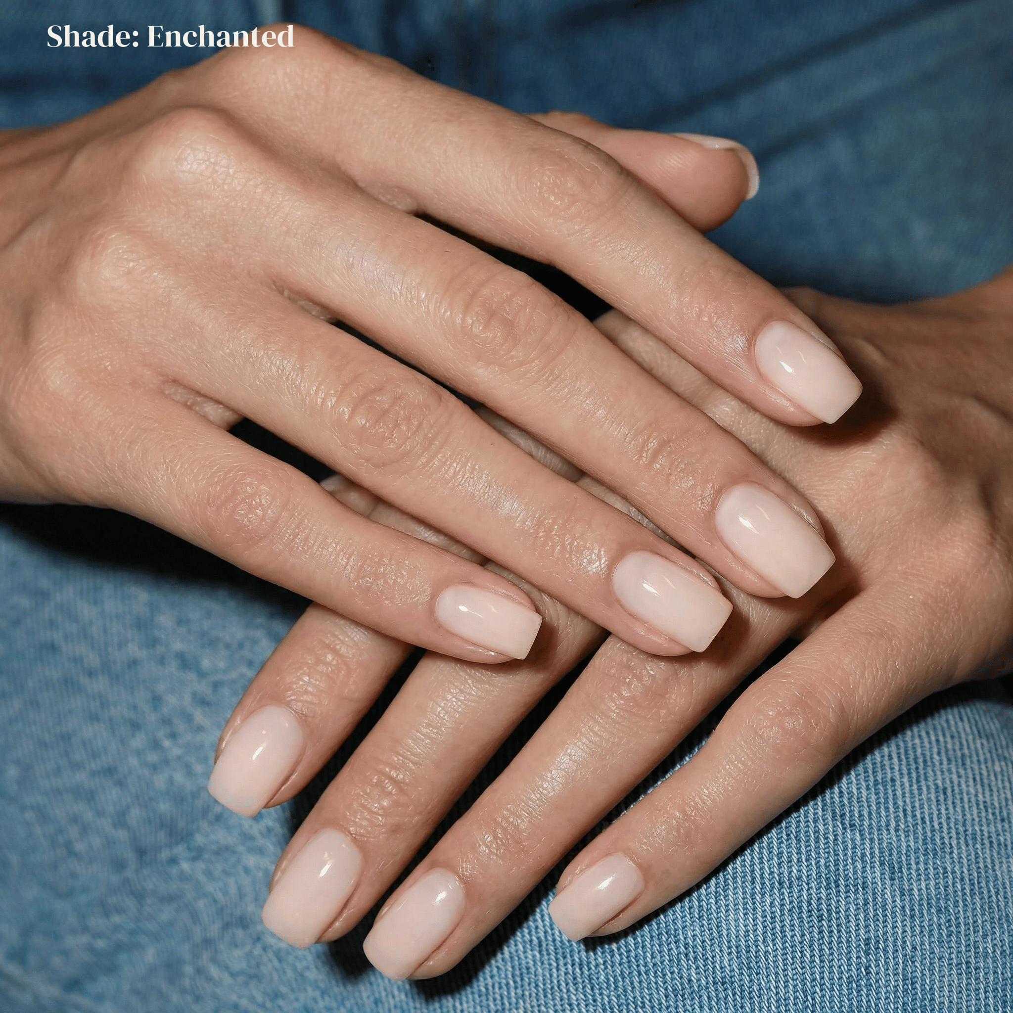 Close-up of hands with light pink nail polish on a blue fabric background