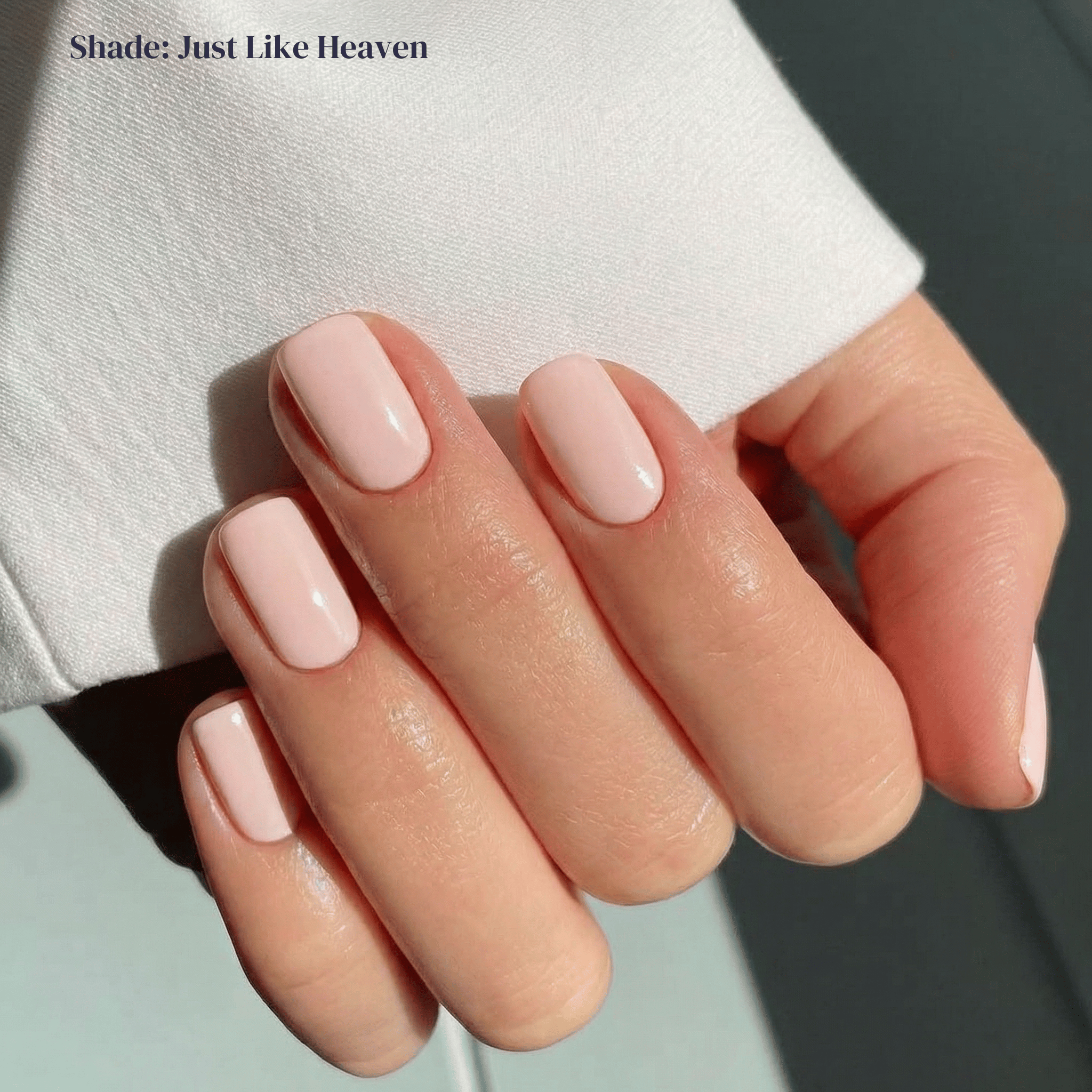 Hand with light pink nail polish on a neutral background