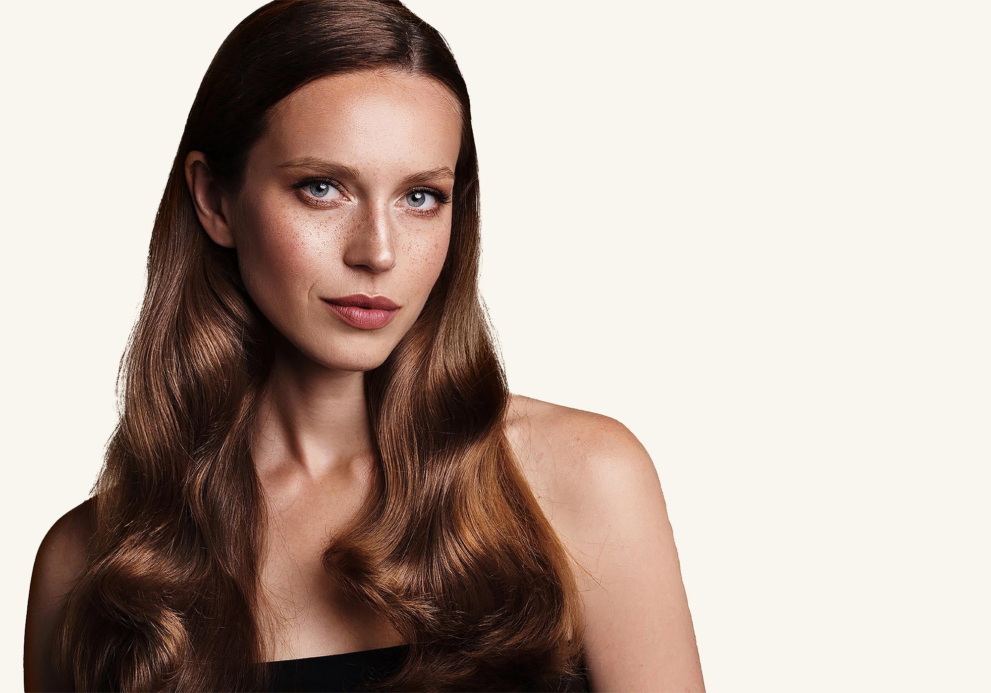 Woman with long, wavy brown hair on a plain background
