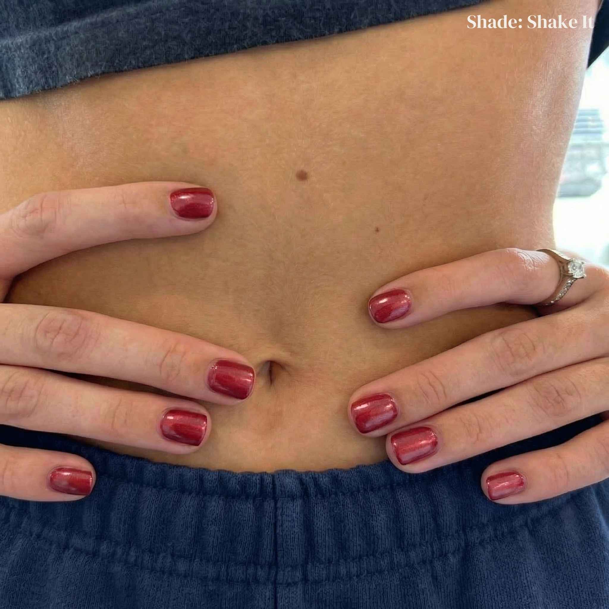 Person wearing blue pants with a visible tattoo on their stomach, holding their waist.